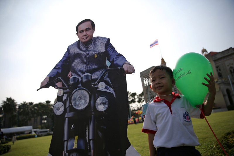 A boy poses next to a cardboard cut-out of Thailand's Prime Minister Prayuth Chan-ocha during preparations for national Children's Day at Government House in Bangkok