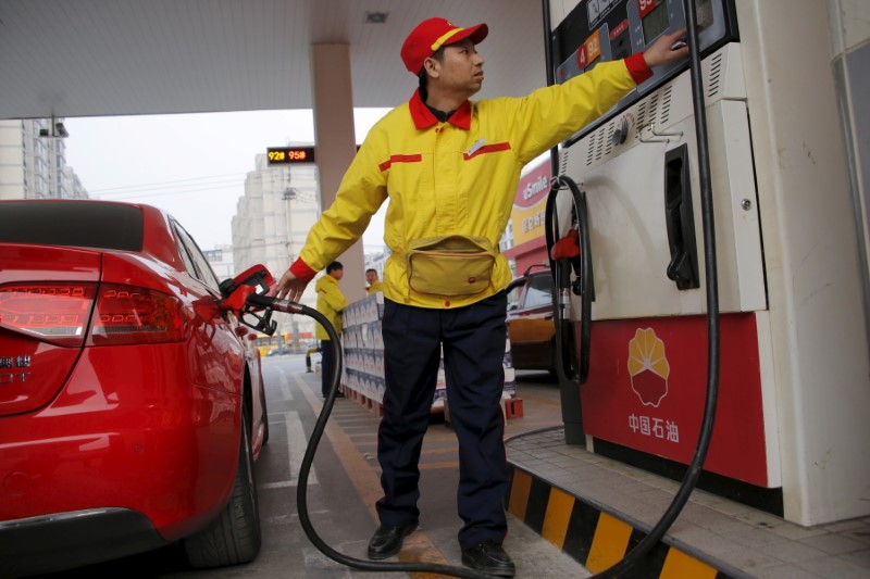 A gas station attendant pumps fuel into a customer's car at PetroChina's petrol station in Beijing