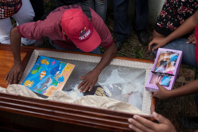 Alexander Conopoy reacts over the coffin of his daughter Alexandra Conopoy, a pregnant 18 year-old killed during an incident over scarce of pork, according to local media, in Charallave