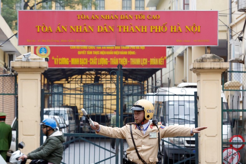 A policeman directs traffic in front of a court in Hanoi