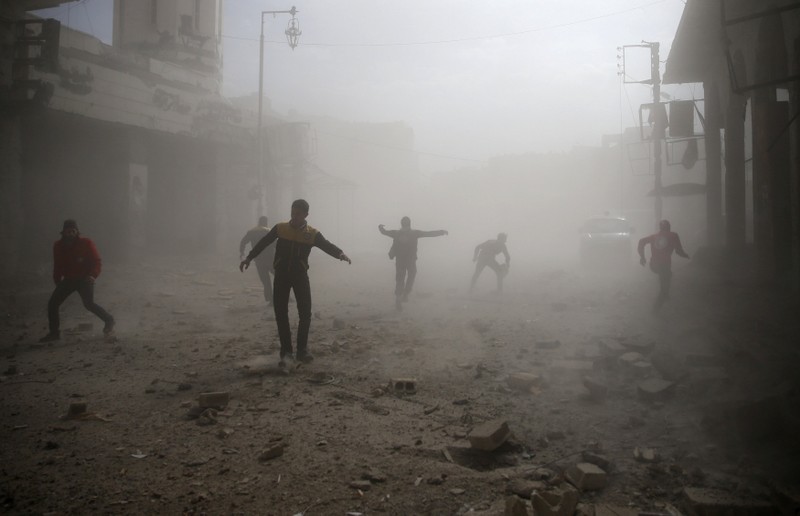 FILE PHOTO: Civil defence members and civilians are seen running after an air raid in the besieged town of Douma in eastern Ghouta in Damascus