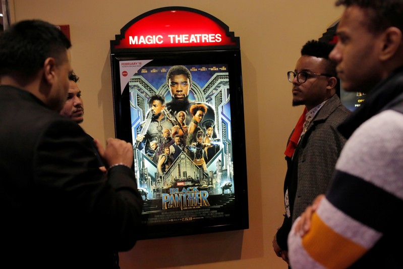 A group of men gather in front of a poster advertising the film 