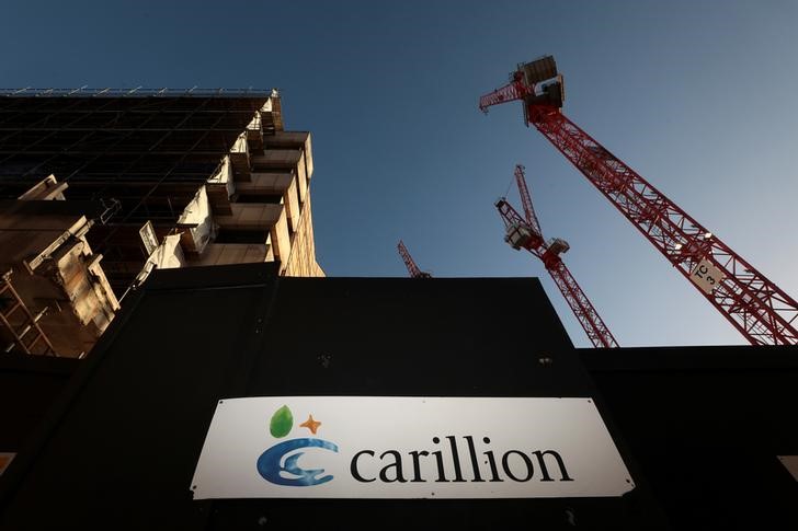 A logo is seen in front of cranes standing on a Carillion construction site in central London