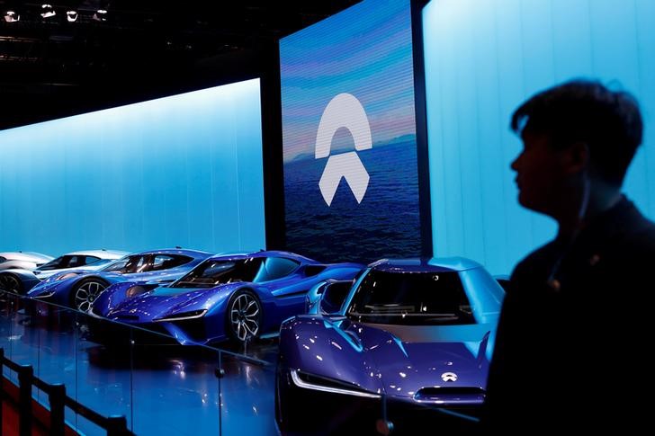 FILE PHOTO: Man is silhouetted in front of Nio cars at auto show in Shanghai