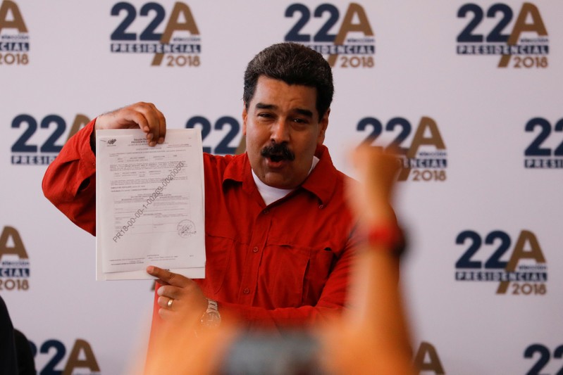 President Nicolas Maduro holds a document as he registers his candidacy for re-election at the National Electoral Council (CNE) headquarters in Caracas