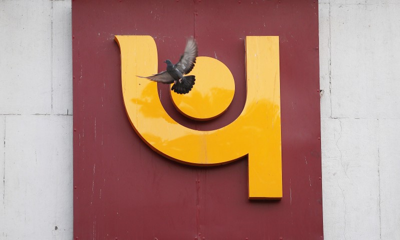 A pigeon flies past the logo of Punjab National Bank outside a branch of the bank in New Delhi