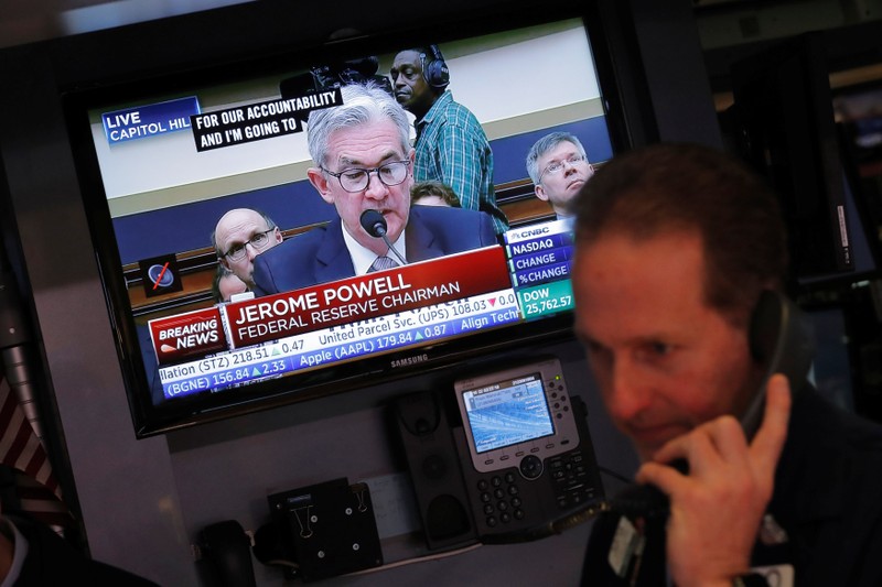 Federal Reserve Chairman Jerome Powell speaks on a television as traders work on the floor of the New York Stock Exchange in New York