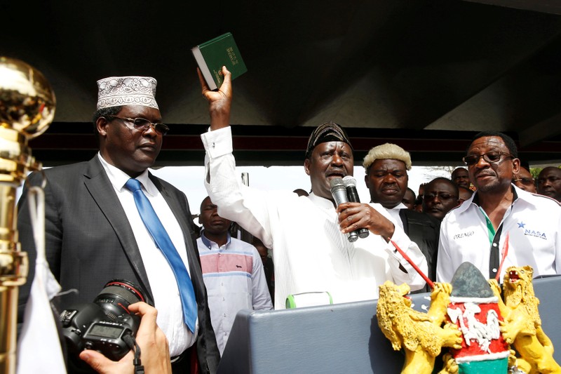 FILE PHOTO: Kenyan opposition leader Raila Odinga of the National Super Alliance is assisted by lawyer Miguna Miguna and James Orengo as he takes a symbolic presidential oath of office in front of his supporters in Nairobi