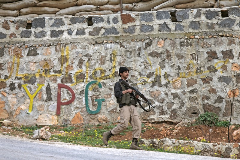 Turkish-backed Free Syrian Army fighter walks as he holds his weapon near the city of Afrin