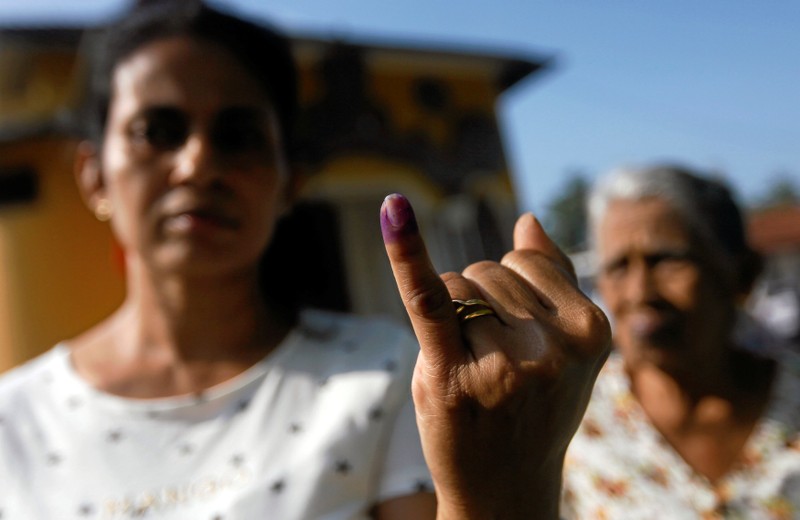 A woman shows her ink-stained finger after casting her vote at a polling station during the long-delayed local government elections in Colombo