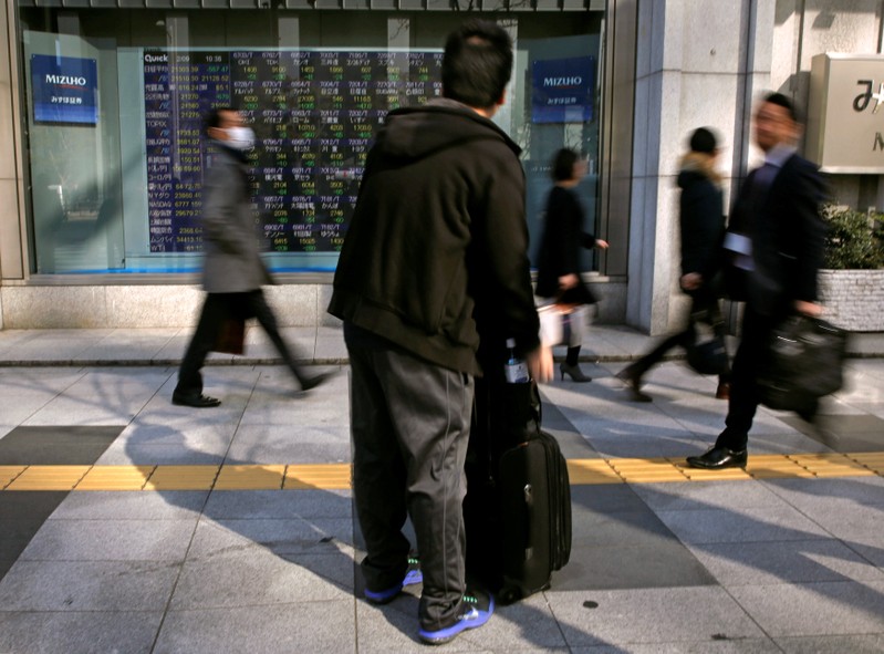 A man looks at an electronic stock quotation board outside a brokerage in Tokyo