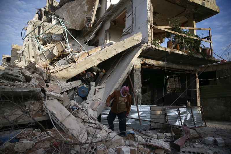 A person inspects damaged building in the besieged town of Douma