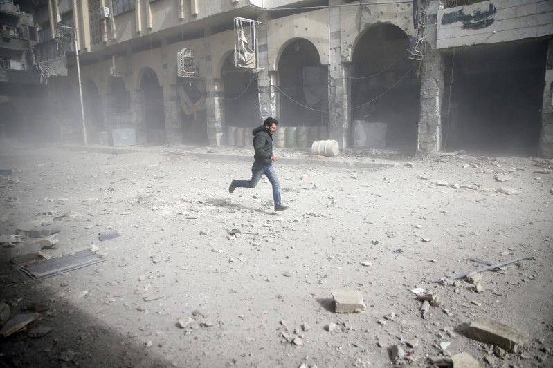 A man is seen running after an air raid in the besieged town of Douma in eastern Ghouta in Damascus