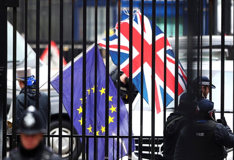 FILE PHOTO: A demonstrator carries a Union Jack and a European Union flag as the EU's chief Brexit negotiator Michel Barnier visits Downing Street in London