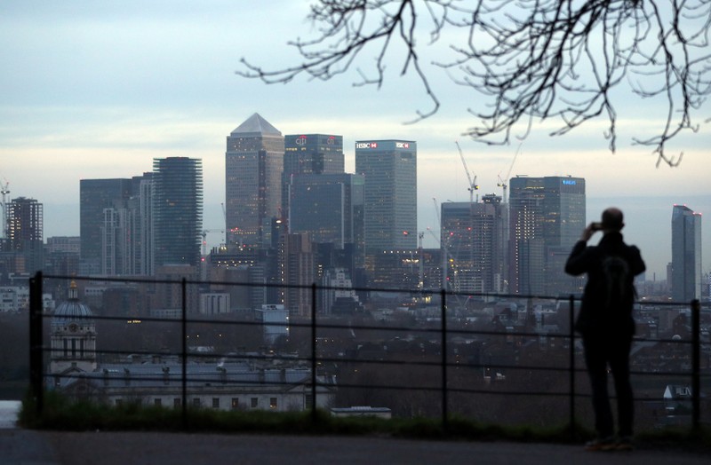 FILE PHOTO: A man takes a photograph of the Canary Wharf financial district from Greenwich Park in London
