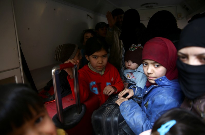 Children hold suitcases during evacuation from the besieged town of Douma