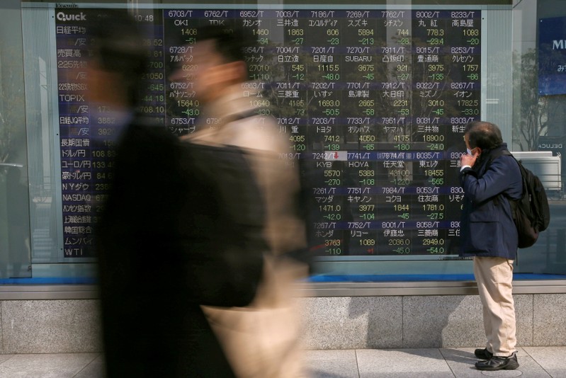 FILE PHOTO: A man looks at an electronic stock quotation board outside a brokerage in Tokyo