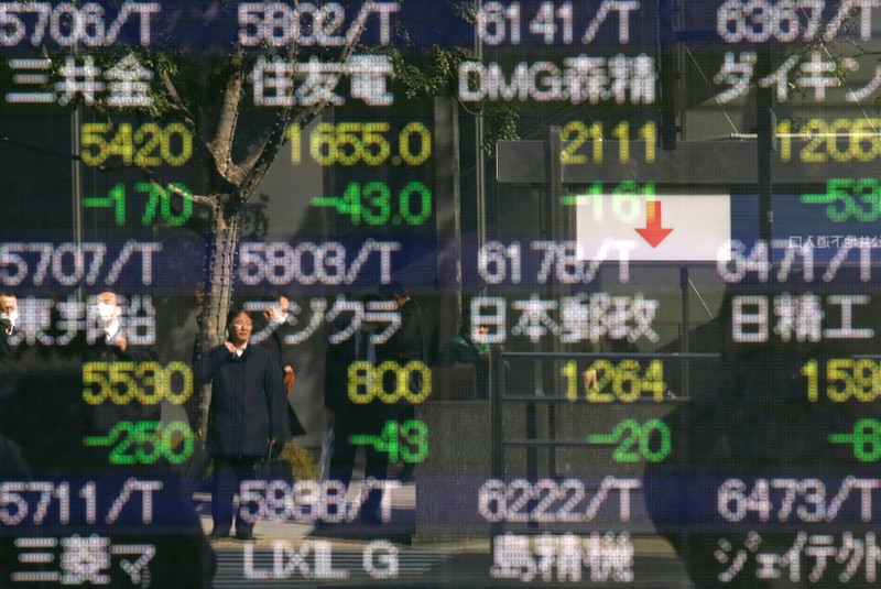FILE PHOTO: A man is reflected in an electronic stock quotation board outside a brokerage in Tokyo