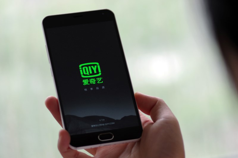 Photo illustration shows a person holding a phone with Baidu Inc's video streaming service iQiyi in Jinan