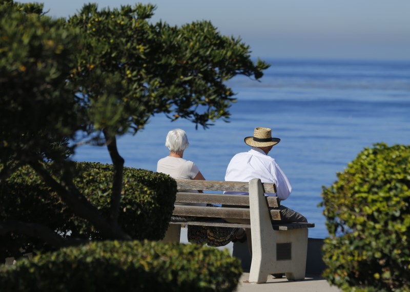 FILE PHOTO: An elderly couple looks out at the ocean as they sit on a park bench in La Jolla, California