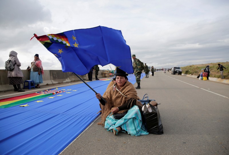 A woman holds a flag during the maritime flag day in la Apacheta