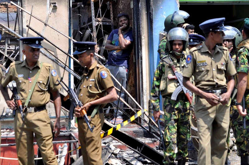 Sri Lanka's Special Task Force and Police officers stand guard near a burnt house after a clash between two communities in Digana, central district of Kandy