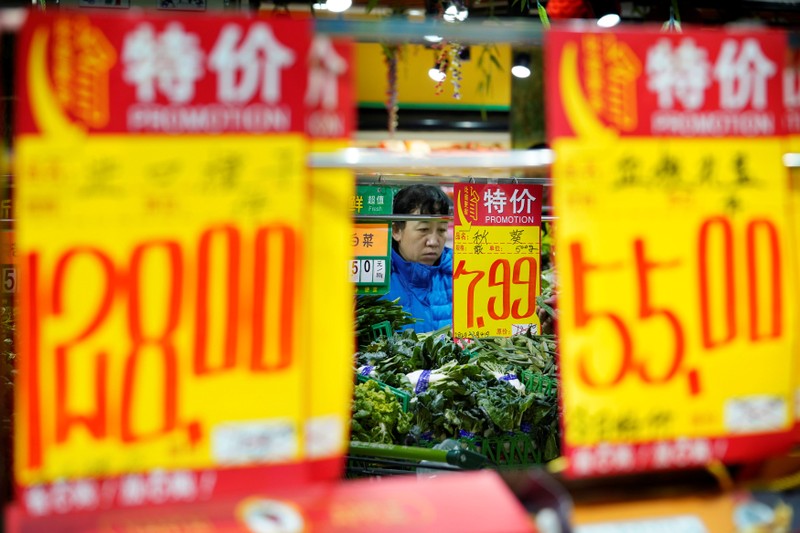 A woman selects vegetables at a supermarket in Beijing