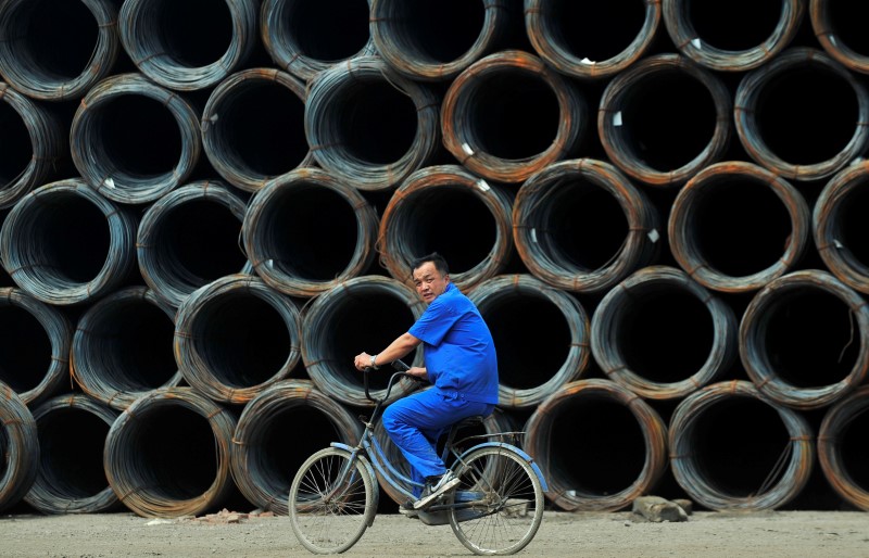 FILE PHOTO - A labourer cycles past coils of steel wire at a steel wholesale market in Shenyang