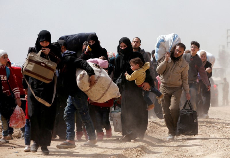 FILE PHOTO: People walk with their belongings as they flee the rebel-held town of Hammouriyeh