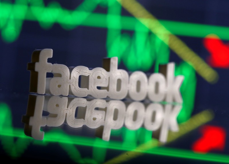 A 3D-printed Facebook logo is seen in front of displayed stock graph