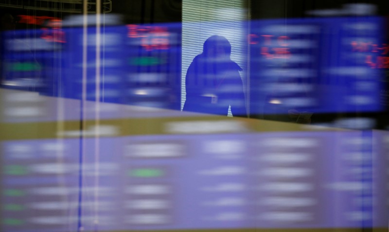 A visitor is seen as market prices are reflected in a glass window at the TSE in Tokyo