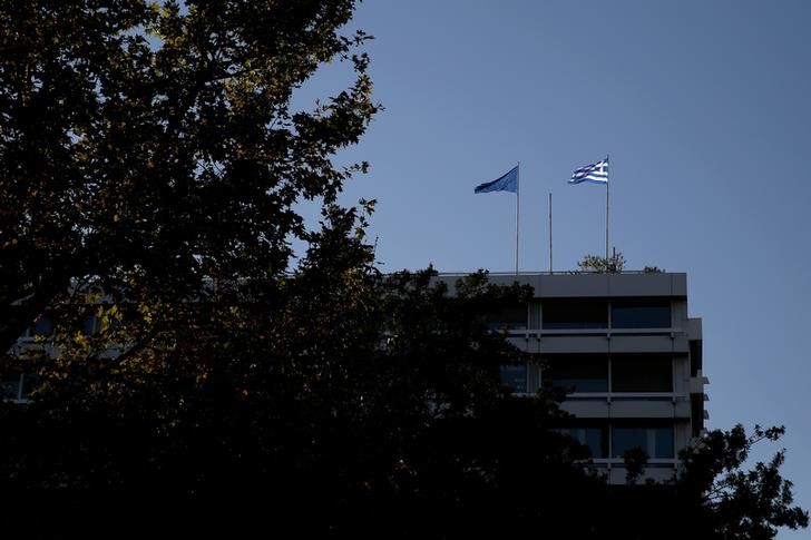 FILE PHOTO - A Greek and a tangled EU flag flutter atop Greece's Financial Ministry in Athens