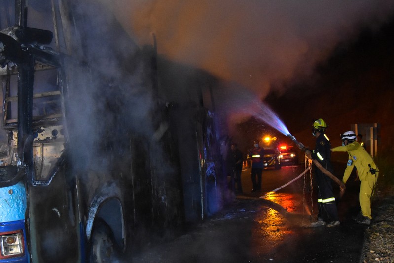 Firefighters extinguish a fire on board a bus in Tak province