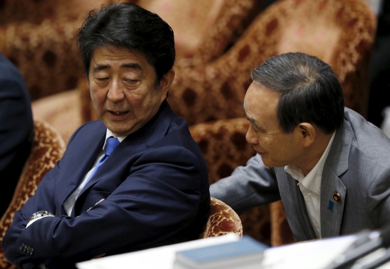 Japan's Prime Minister Abe talks with Chief Cabinet Secretary Suga at a lower house special committee session on security-related legislation at the parliament in Tokyo