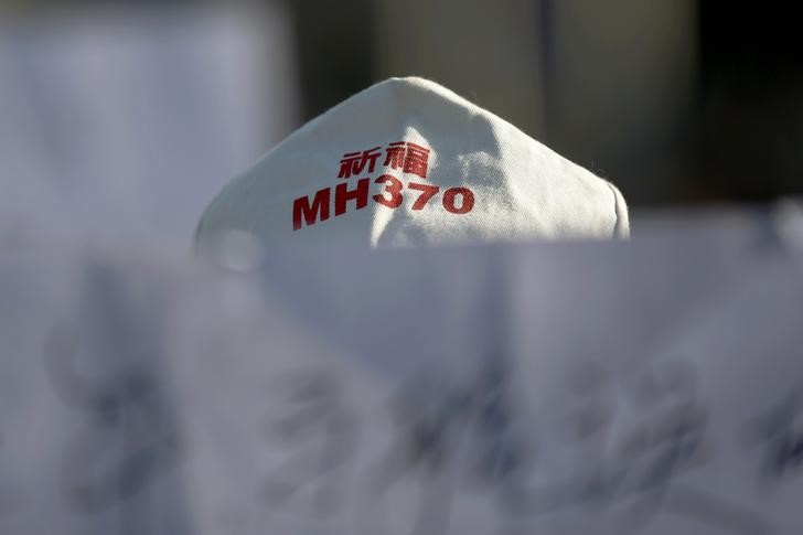 FILE PHOTO: A family member of a passenger onboard Malaysia Airlines flight MH370 holds a banner during a gathering in front of the Malaysian Embassy in Beijing