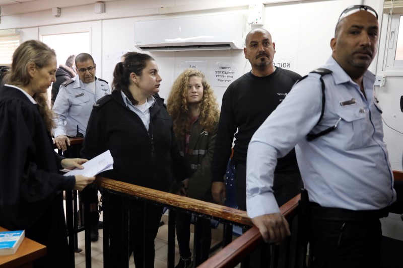 Palestinian teen Ahed Tamimi enters a military courtroom escorted by Israeli security personnel as her lawyer Gaby Lasky stands near, at Ofer Prison, near the West Bank city of Ramallah