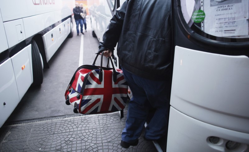 A man carrying a bag adorned with a British Union Jack flag steps into bus departing from Sofia's central bus station to London