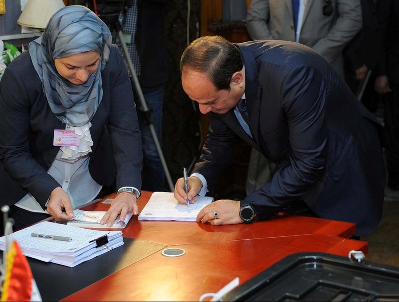 Egyptian President Abdel Fattah al-Sisi writes as he arrives to cast his vote during the presidential election in Cairo