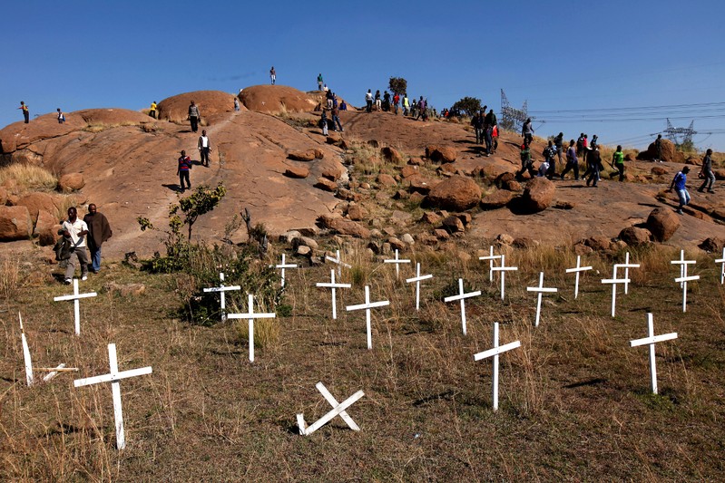 FILE PHOTO: Members of the mining community walk near crosses placed at a hill known as the 