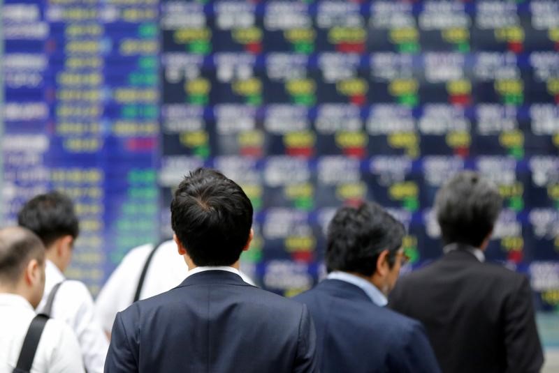 FILE PHOTO - People walk past an electronic stock quotation board outside a brokerage in Tokyo