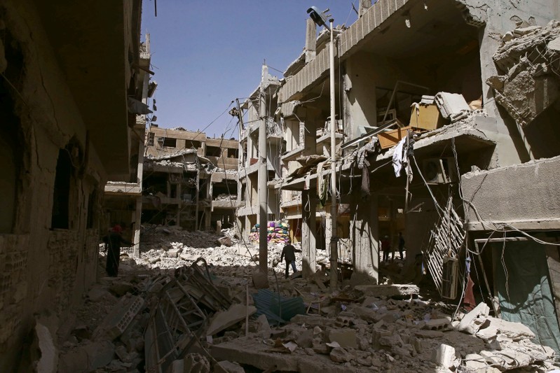 A man walks on rubble of damaged buildings in the besieged town of Douma