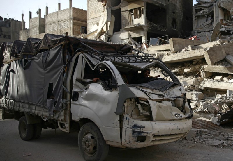 Men sit in a damaged truck in the besieged town of Douma in eastern Ghouta in Damascus