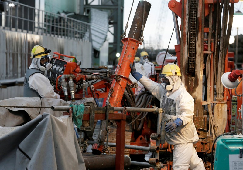 FILE PHOTO: Workers prepare frozen pipes during operations to construct an underground ice wall at Tepco's tsunami-crippled Fukushima Daiichi nuclear power plant