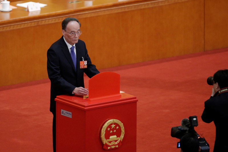 Wang Qishan, former secretary of the Central Commission for Discipline Inspection, drops his ballot during a vote at the fifth plenary session of the National People's Congress (NPC) at the Great Hall of the People in Beijing