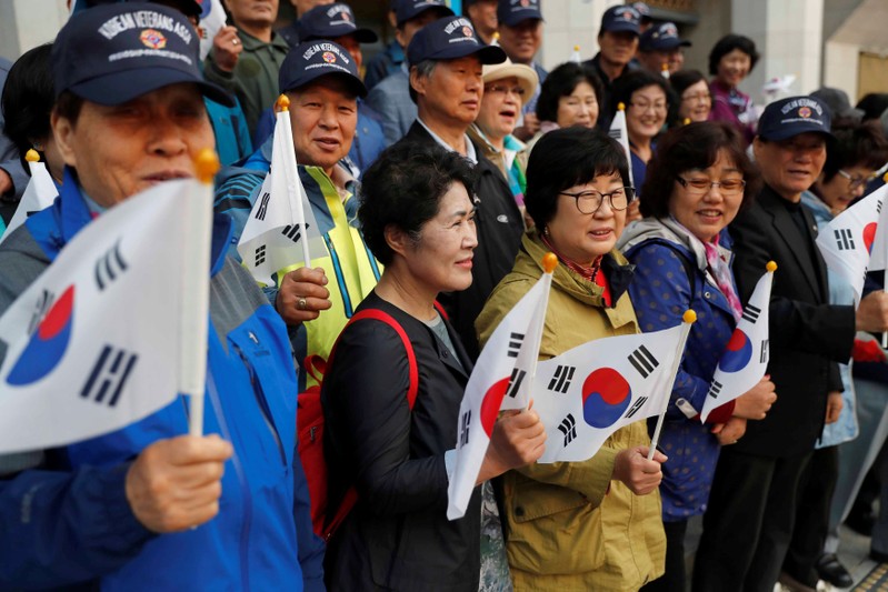 Supporters hold South Korean flags while waiting for a convoy transporting South Korean President Moon Jae-in to leave the Presidential Blue House for the inter-Korean summit, in Seoul