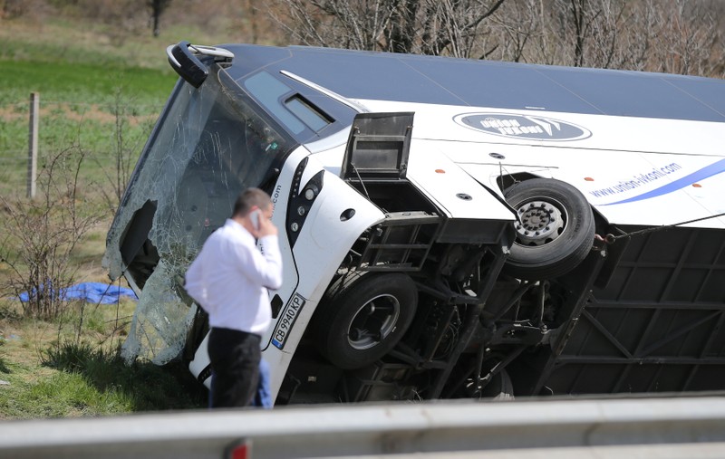 A man walks beside a crashed bus on a highway near capital Sofia