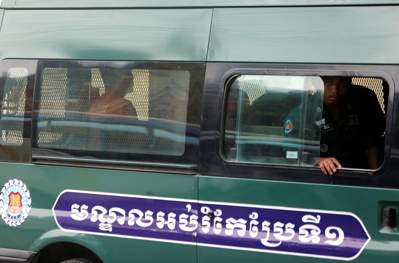 Uon Chhin and Yeang Sothearin, former journalists of the Radio Free Asia (RFA), seat inside a police vehicle as they arrive for a bail hearing at the Appeal Court in Phnom Penh