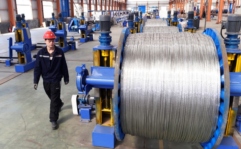 A worker walks past aluminium wires at a plant inside an industrial park in Binzhou