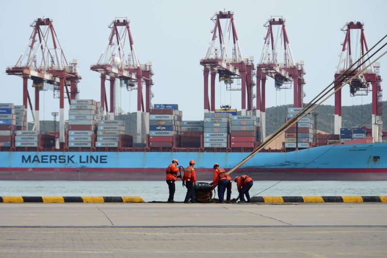 Workers help to dock a cargo ship at a port in Qingdao