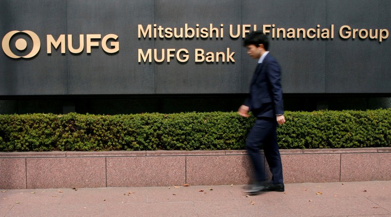 FILE PHOTO: A man walks past a signboard of Mitsubishi UFJ Financial Group and MUFG Bank at its headquarters in Tokyo